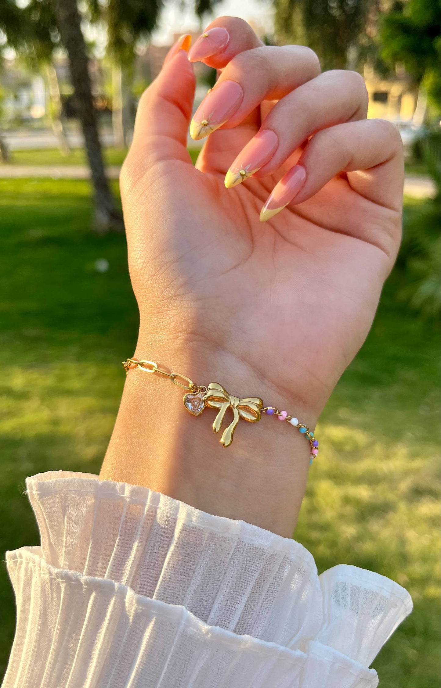 إسورة مطلية بالذهب بتصميم فيونكة مزينة بقلادة قلب وخرز ملون