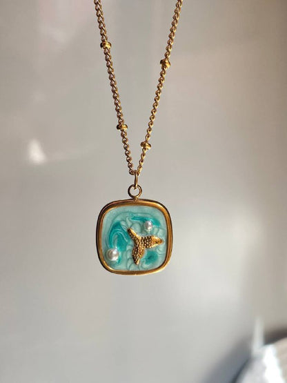 عقد بتعليقة صدفة باللون الذهبي مزينة بمينا زرقاء ولآلئ تقليدية