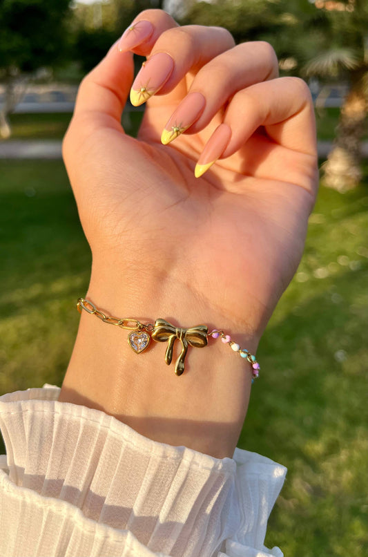 إسورة مطلية بالذهب بتصميم فيونكة مزينة بقلادة قلب وخرز ملون