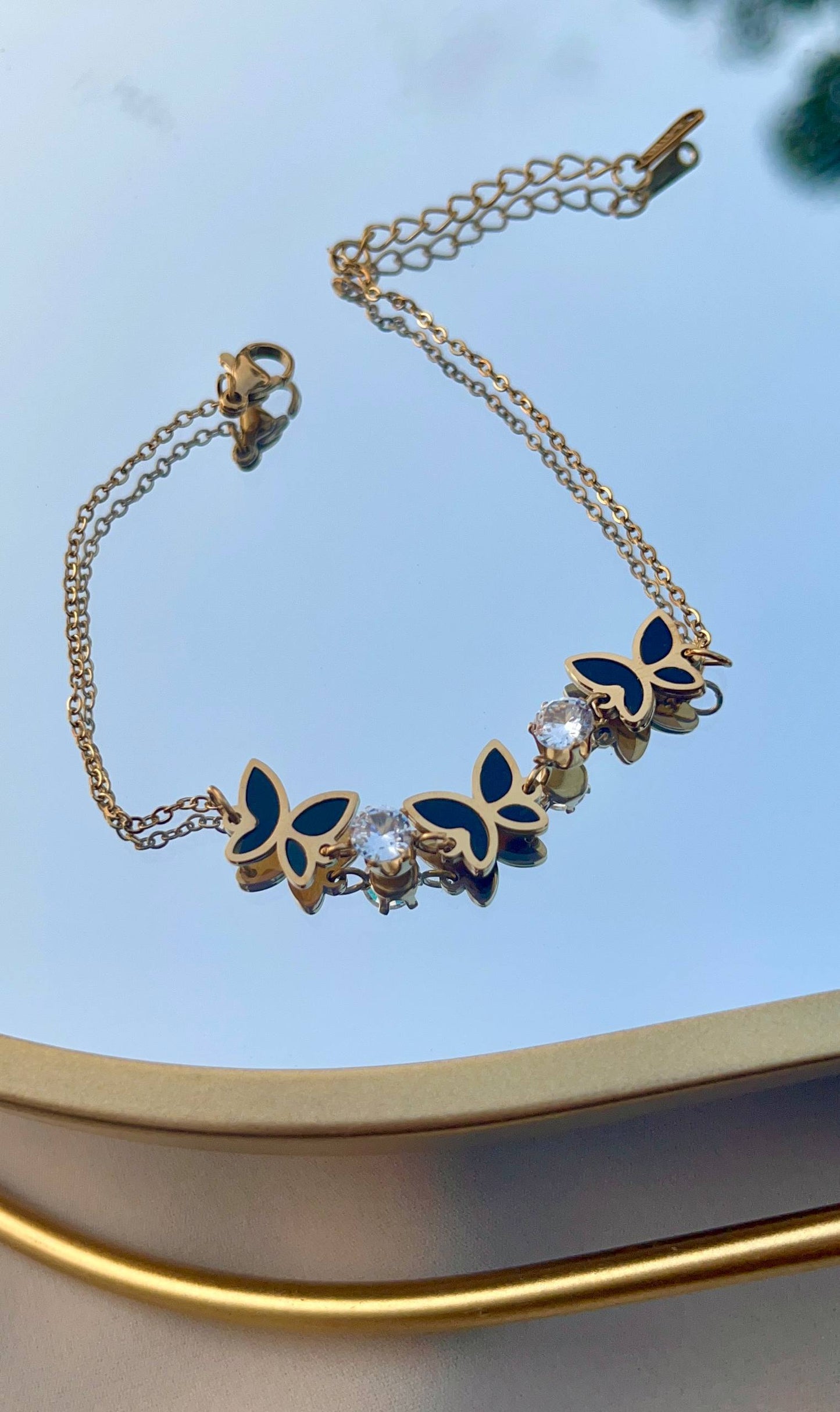 إسورة فراشة ستانلس بيور ذهبي مع تفاصيل سوداء وحبيبات كريستال لامعة