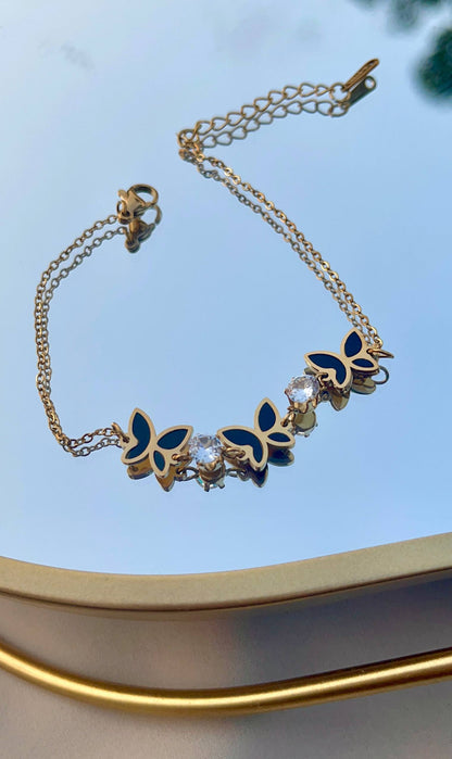 إسورة فراشة ستانلس بيور ذهبي مع تفاصيل سوداء وحبيبات كريستال لامعة