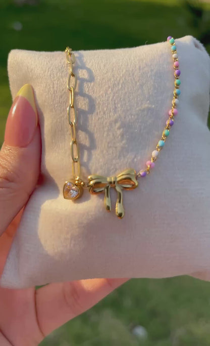إسورة مطلية بالذهب بتصميم فيونكة مزينة بقلادة قلب وخرز ملون